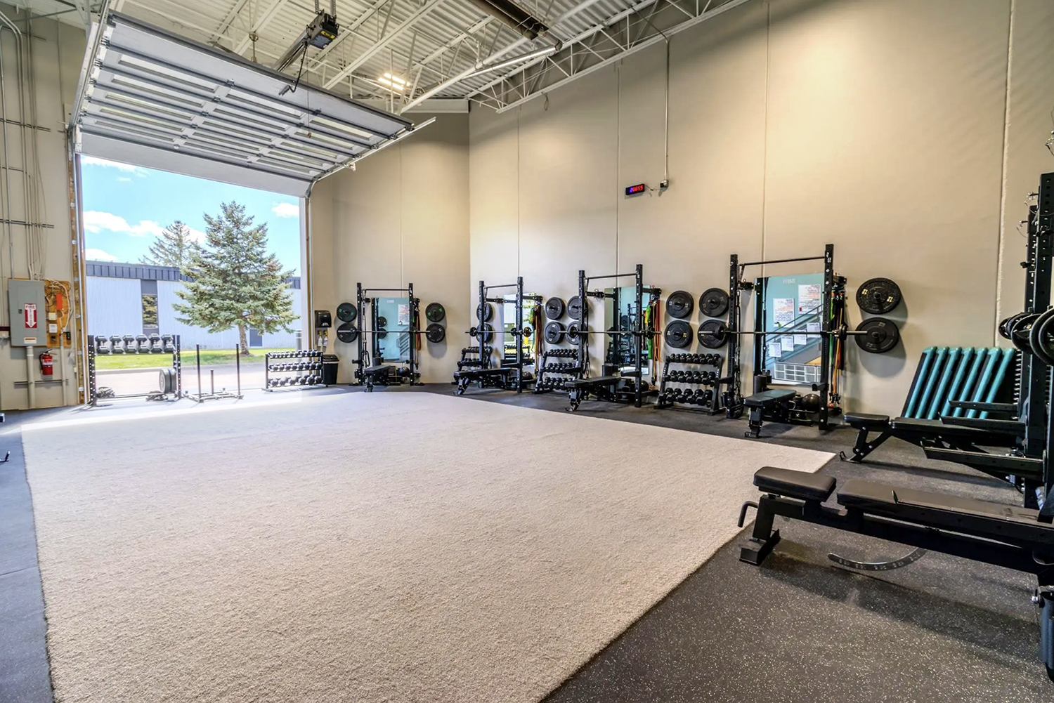Open garage door letting daylight into the Elevate weight room