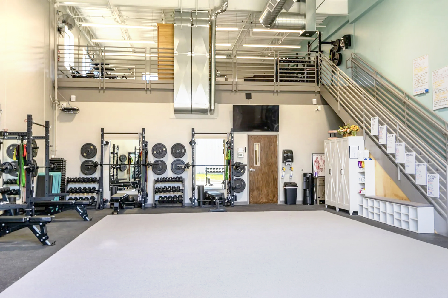 Two-story Elevate gym interior with racks and a loft